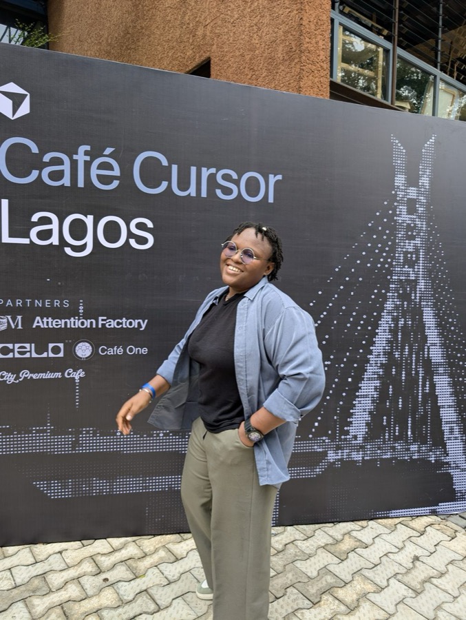 Faith Nwaubani, founder of GrowNowNow, smiling in front of the Café Cursor Lagos event signage